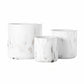 A set of three white ceramic round pots with a matte finish and abstract designs