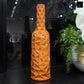 A glossy orange wrinkled ceramic vase with a tall, round bottle shape displayed on a table.