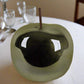 Cat toy shaped like a green apple with a hole for a cat to fit inside on a white background