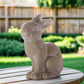 Concrete rabbit statue on a wooden surface with a garden background