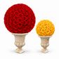 Two decorative floral topiary spheres on stone-style pedestals, one large red rose ball and one smaller yellow rose ball, photographed on a clean white background.
