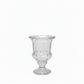A clear glass pedestal cup with a flared rim, subtle scalloped edge detailing, and a fluted body, shown on a plain white background.