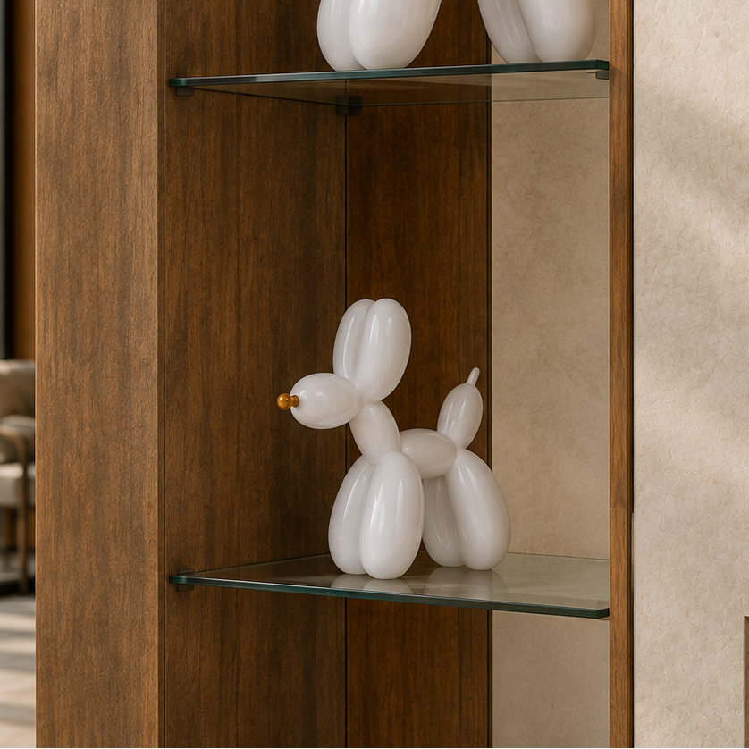 A white balloon-bubble dog sculpture displayed on a glass shelf inside a wooden cabinet, with a beige textured wall in the background.