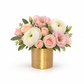 A floral arrangement featuring pink and white flowers with green leaves, presented in a textured gold cylindrical pot against a clean white background.