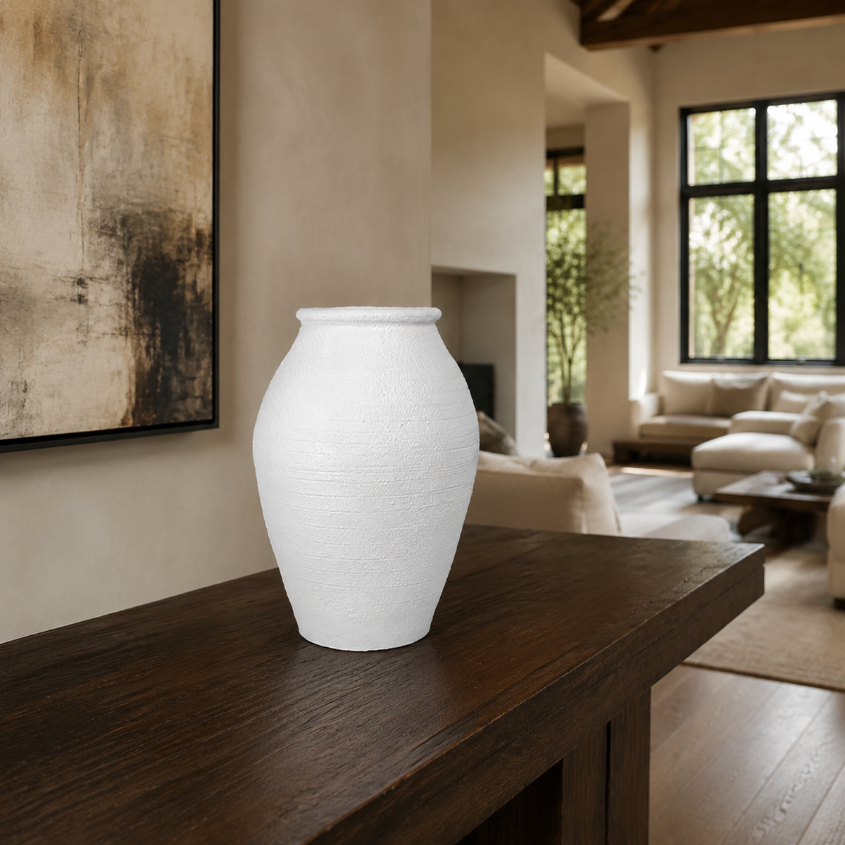 A white textured ceramic vase with a rounded bulbous shape, displayed on a dark wooden console table in a modern, warm-toned living room.